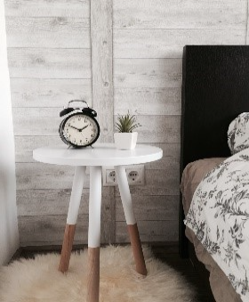 black alarm clock at 10:10 on white wooden table near table